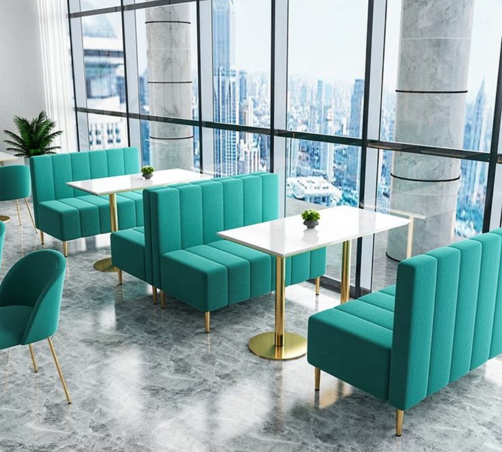 Divanetti color petrolio e tavoli vicino alle vetrate del caffè