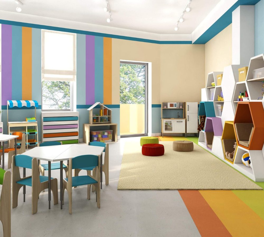 Kindergartenraum mit Tischen, Regalen und Kuschelecke