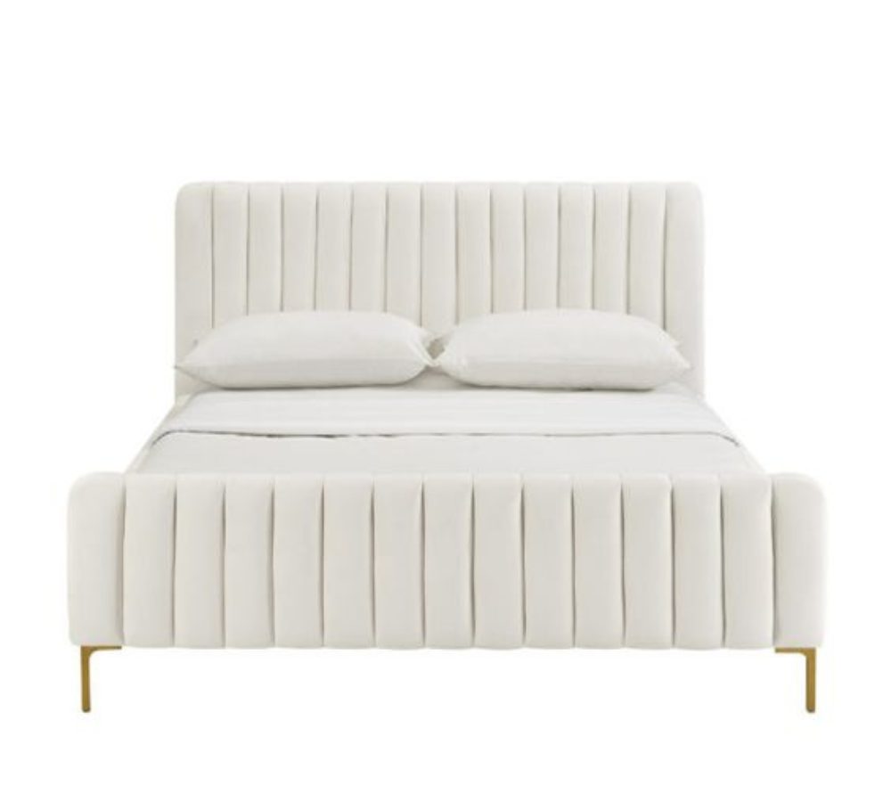 White upholstered bed with vertical stitching on brass legs
