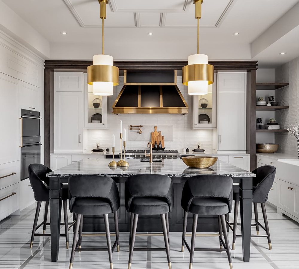 Kitchen with a black island, brass pendants and range hood