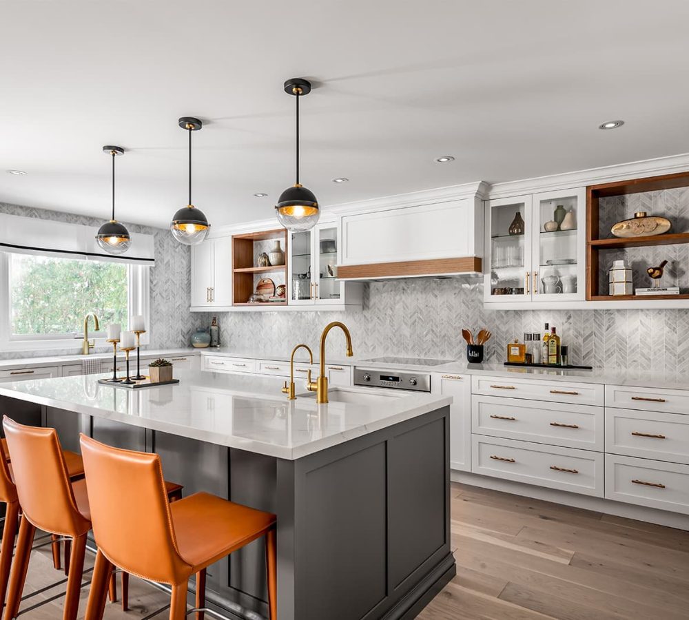 White kitchen with a dark island and orange bar stools