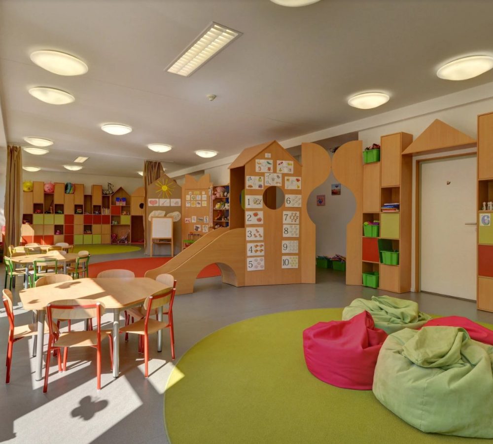 Kindergartenraum mit Spielhäusern, Tischen und Sitzsäcken