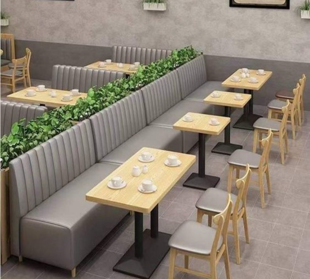 Divanetti grigi con fioriere divisorie e tavoli nel caffè