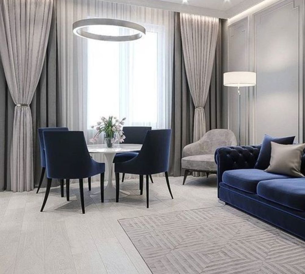 Soggiorno grigio con zona pranzo e divano in velluto blu