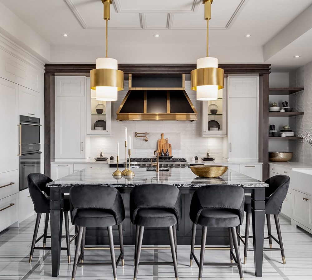 Kitchen with a black island, brass pendants and range hood