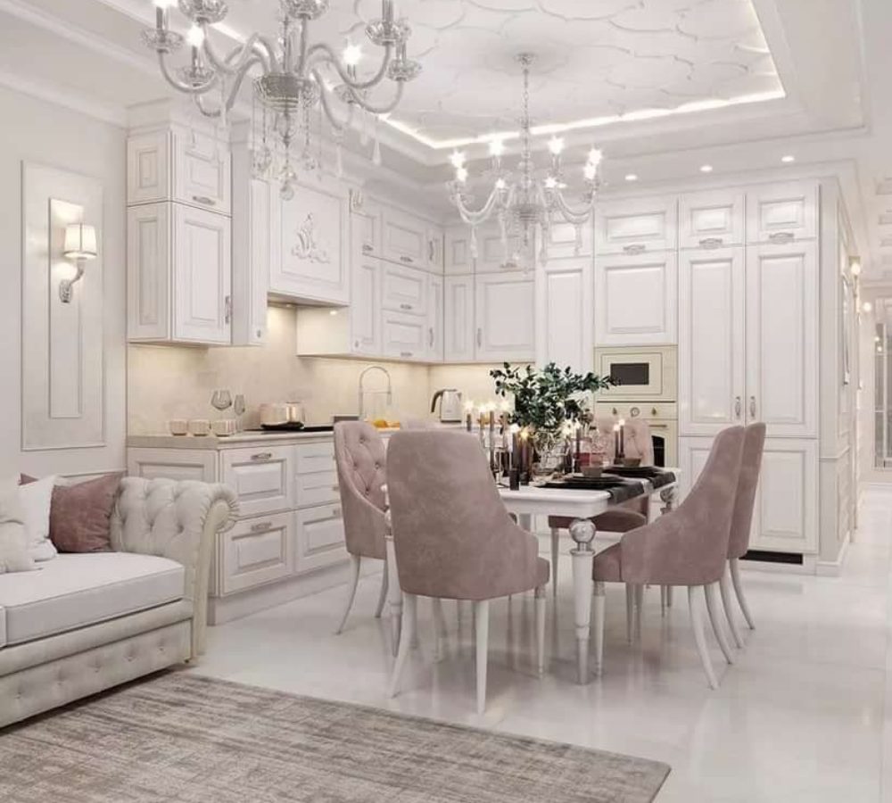 White open-plan kitchen with a dining table and pink chairs