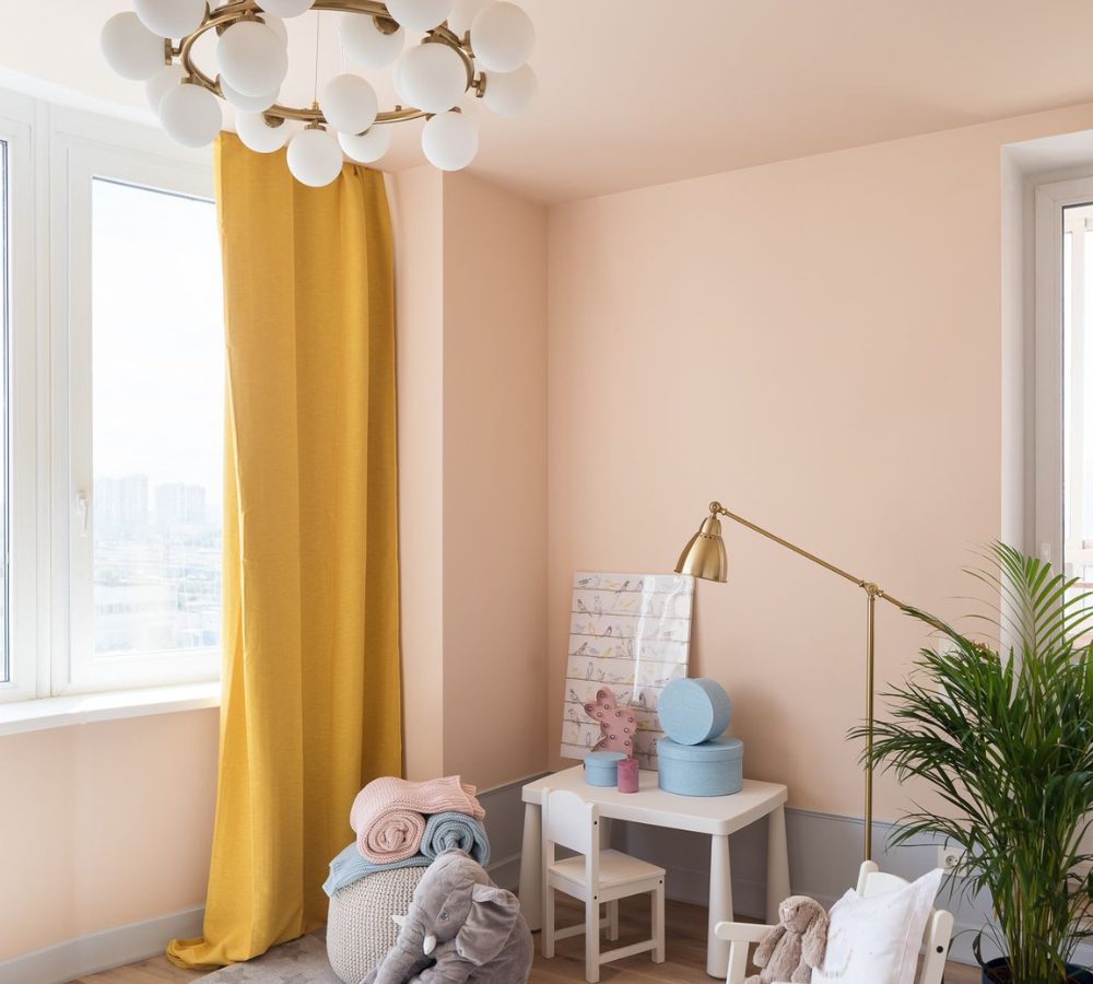 Pfirsichfarbenes Kinderzimmer mit Schreibtisch und gelben Vorhängen